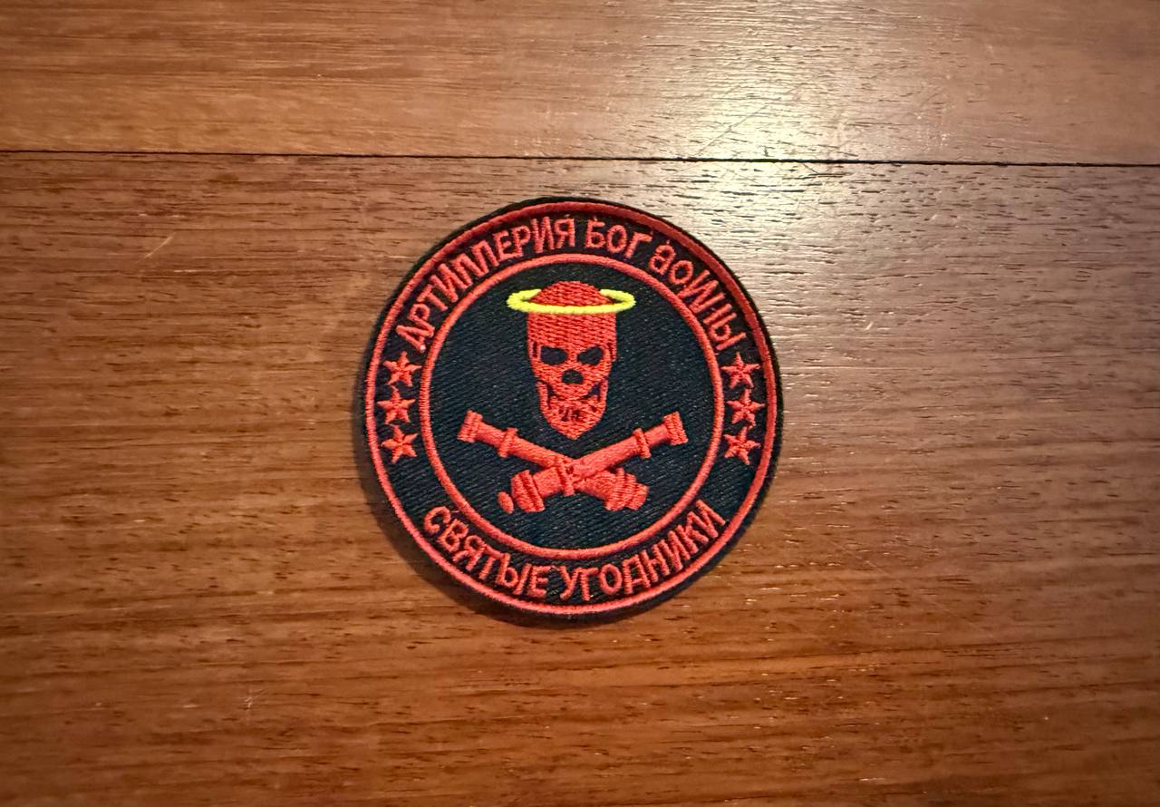 Embroidered patch with skull and crossbones design on a wooden surface