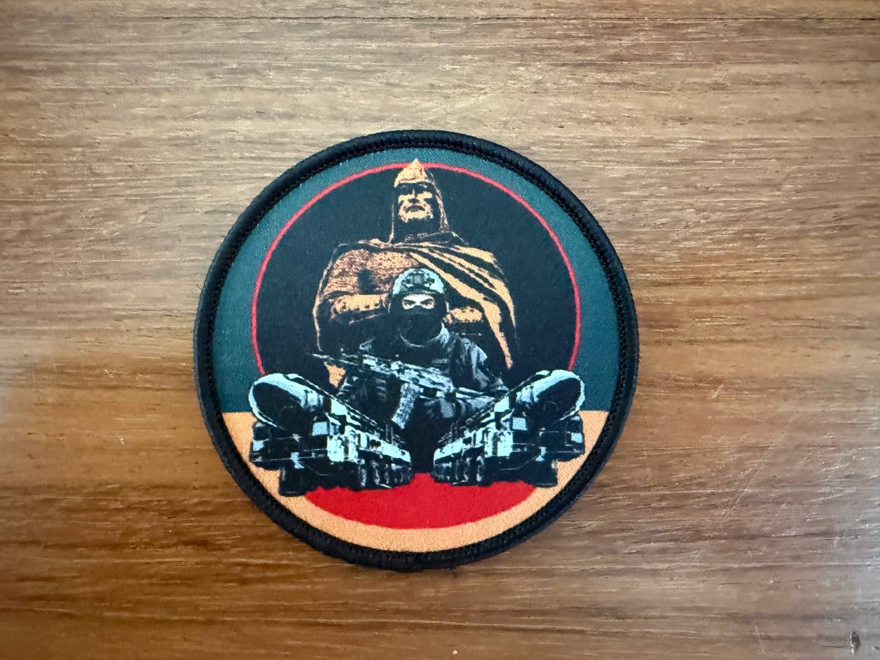 Circular patch with a design of a person in a helmet and mask on a wooden surface