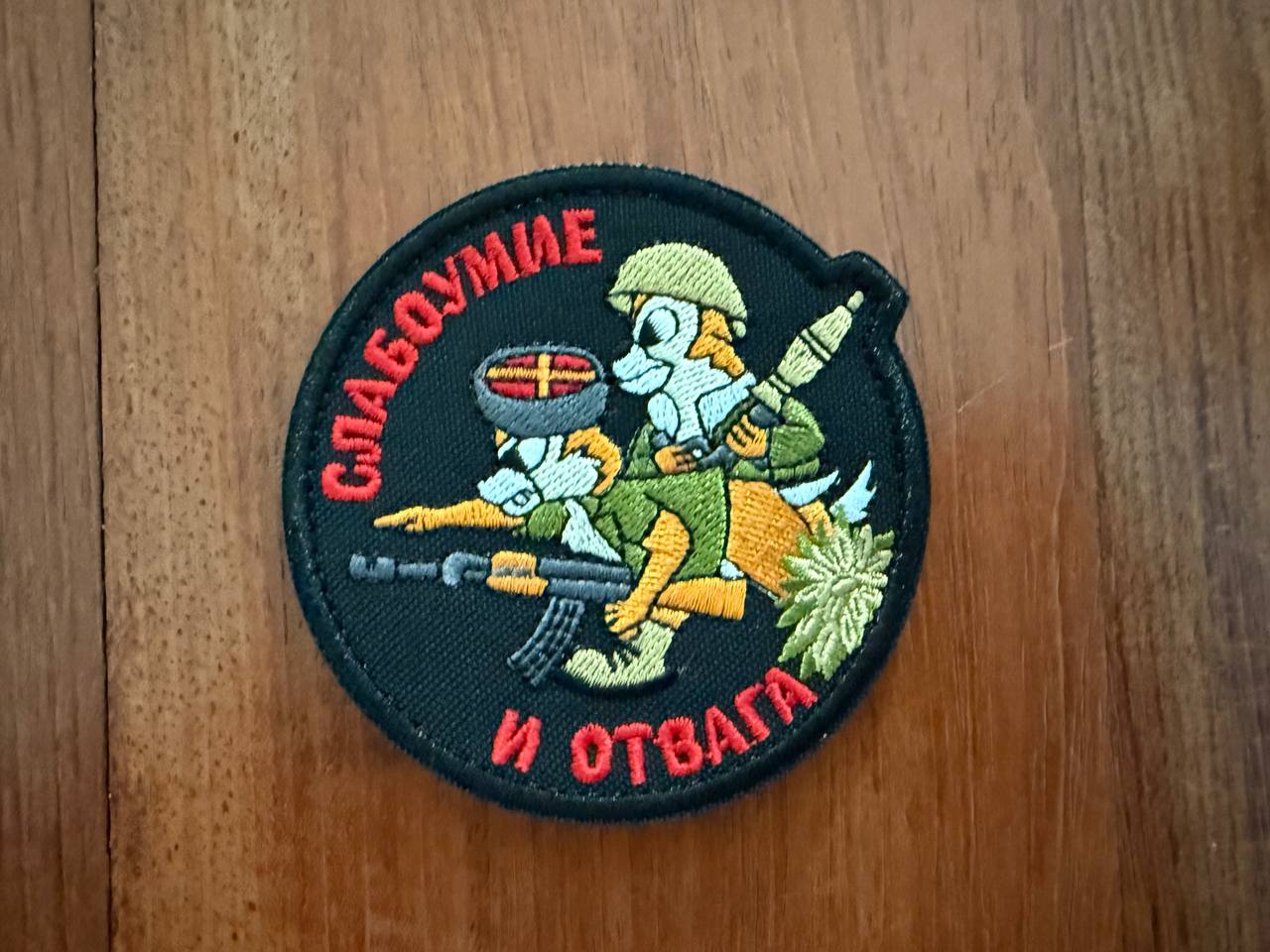 Circular patch with cartoon characters and text on a wooden surface