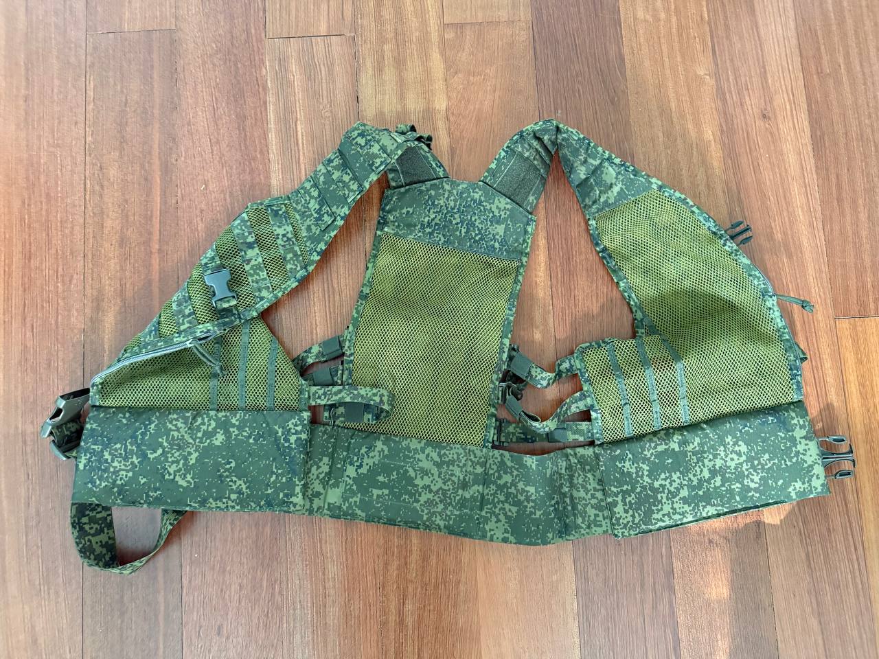 Green camouflage tactical vest on a wooden floor