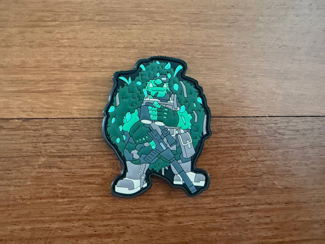 Decorative patch of a character with green and gray design on a wooden surface