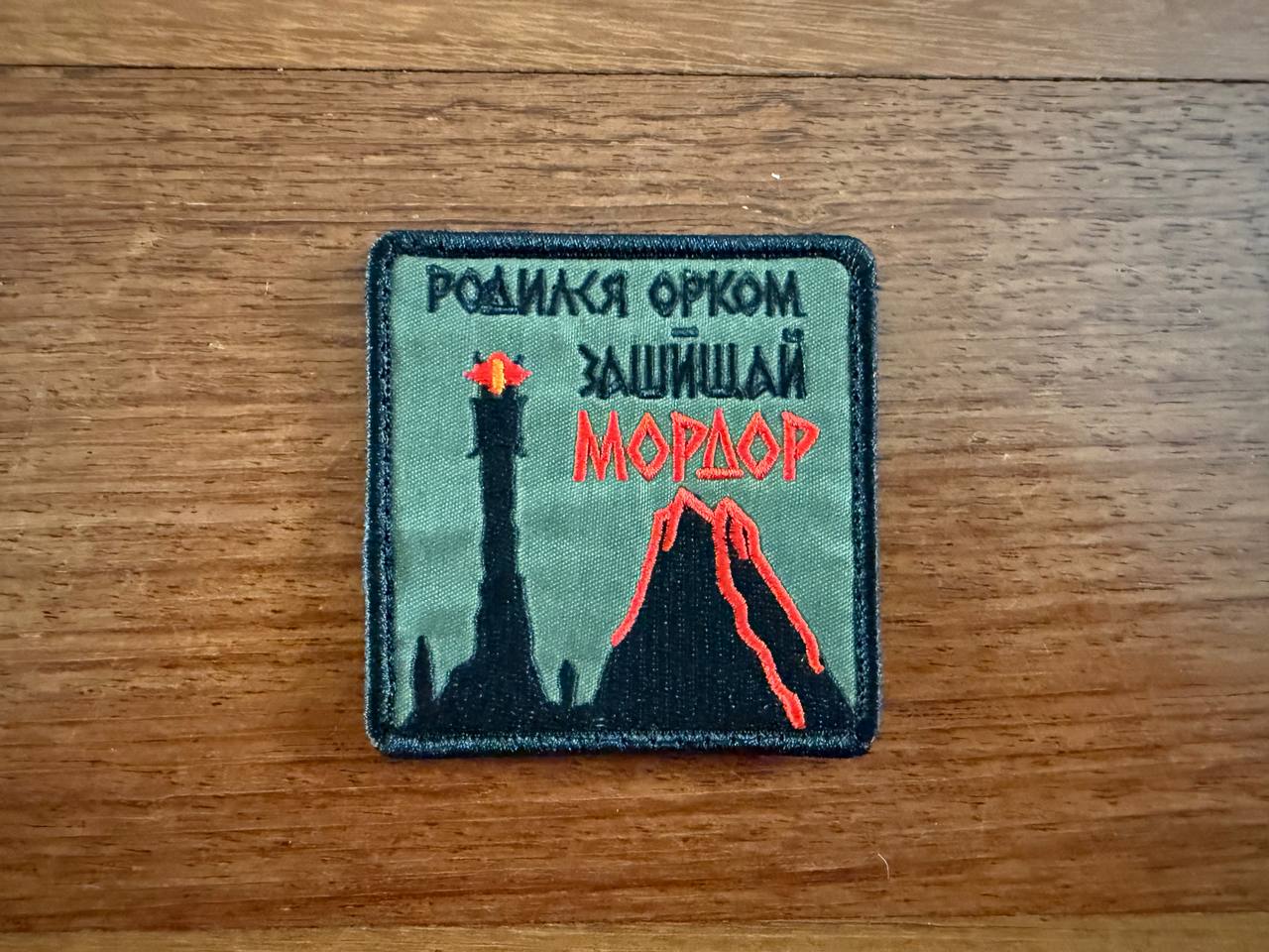 The Tanki Store Russian LOTR Reference Born an Orc, Defend Mordor Patch features the Eye of Sauron, a tower, a lava volcano, and the phrase Родился орком, защищай Мордор. Collect these unique patches in a set!.