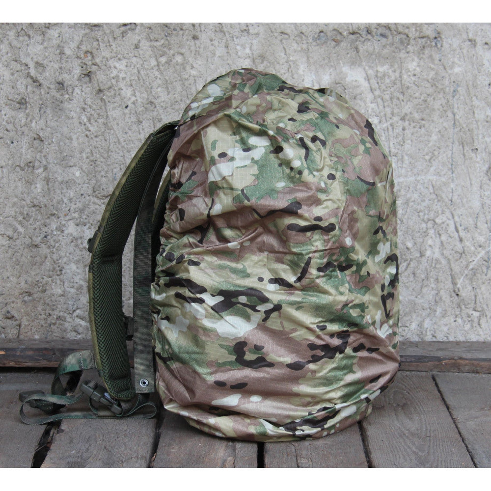 Camouflage backpack on a wooden surface with a concrete wall background