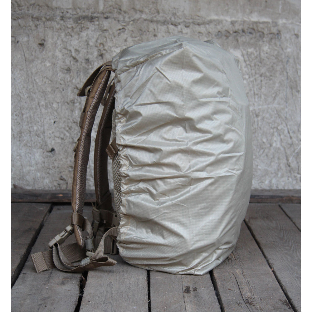 Backpack with a beige cover on a wooden surface and concrete wall background