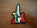 Colorful patch with a design of a character holding a weapon on a wooden surface