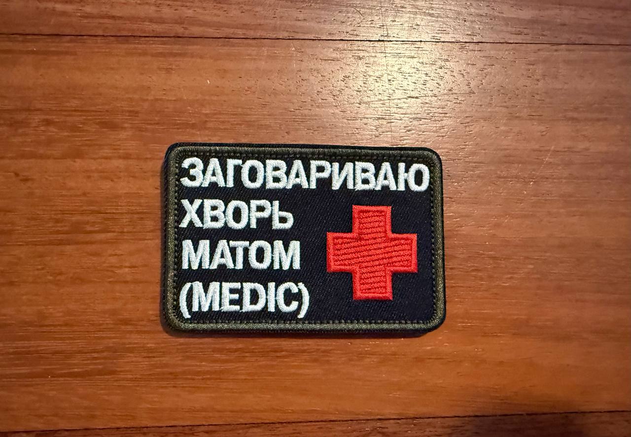 Patch with text and red cross on a wooden surface