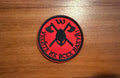 Red and black patch with crossed axes and text on a wooden surface