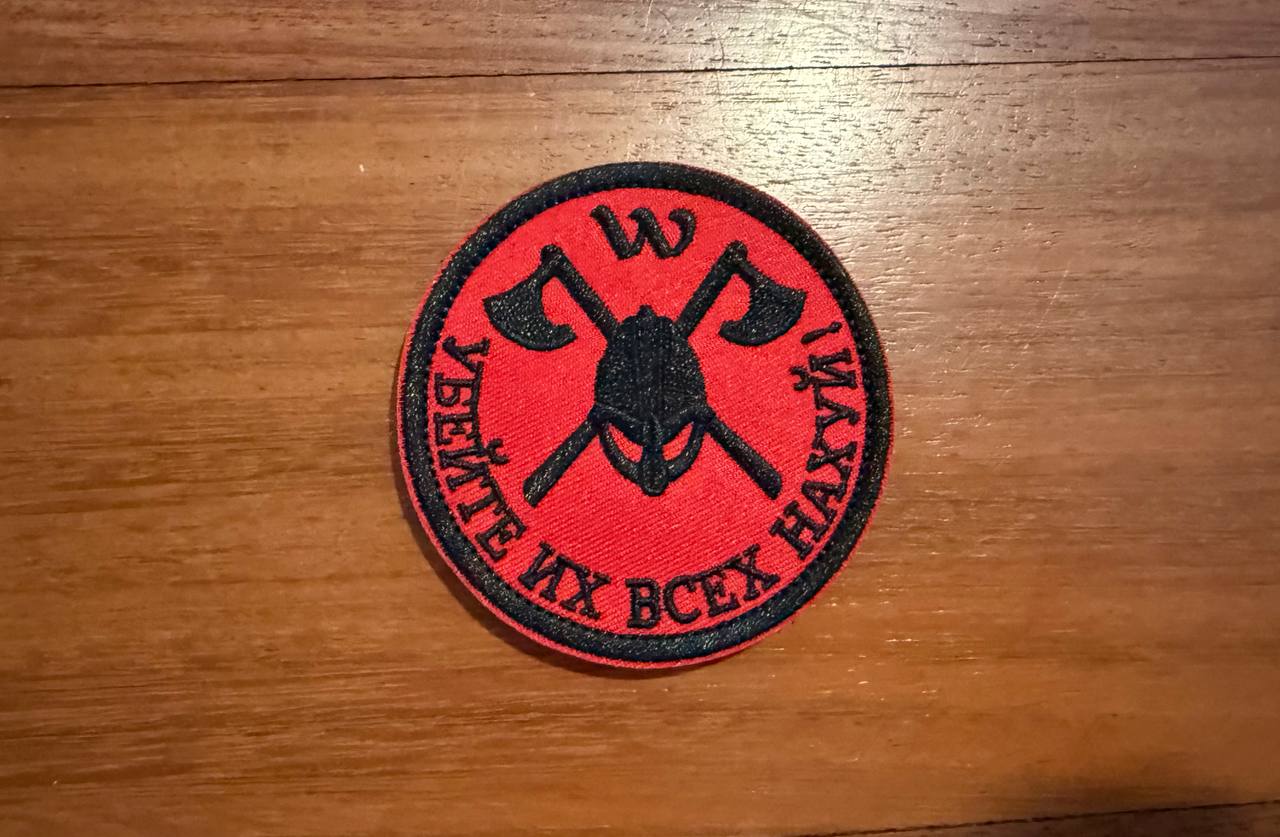 Red and black patch with crossed axes and text on a wooden surface
