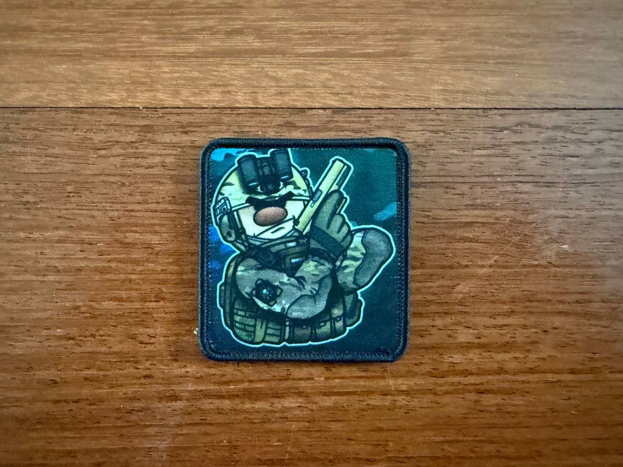 The Russian Cartoon-Style Soldier Design Patch – Military Badge by Tanki Store features a cartoon soldier in camo with a rifle on a blue background. Ideal for collectors or bulk orders seeking the best price.
