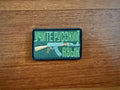 The Learn Russian Language Green/Camo Patch by Tanki Store features a rifle illustration and Russian text on fabric, making it a great military badge for collectors or bulk purchases.