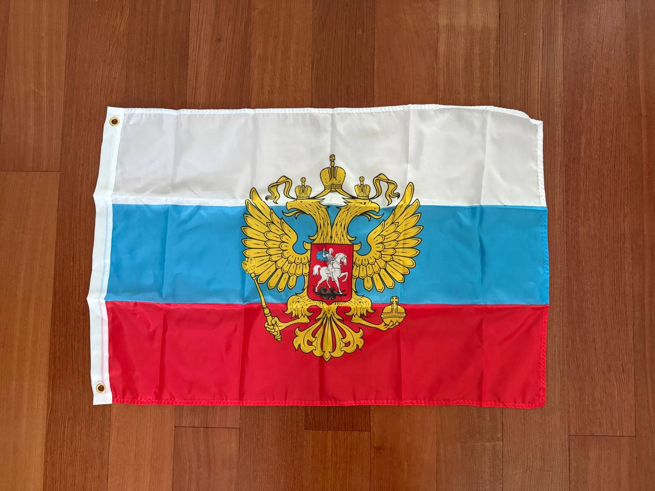 Flag with a double-headed eagle emblem on a wooden surface