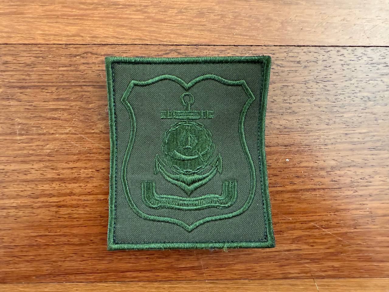 The 80th Arctic Motor Rifle Brigade Russian Army Field Patch by Tanki Store features a green embroidered anchor and shield emblem. This monochrome military badge is displayed on wood and available in large quantities at the best price.