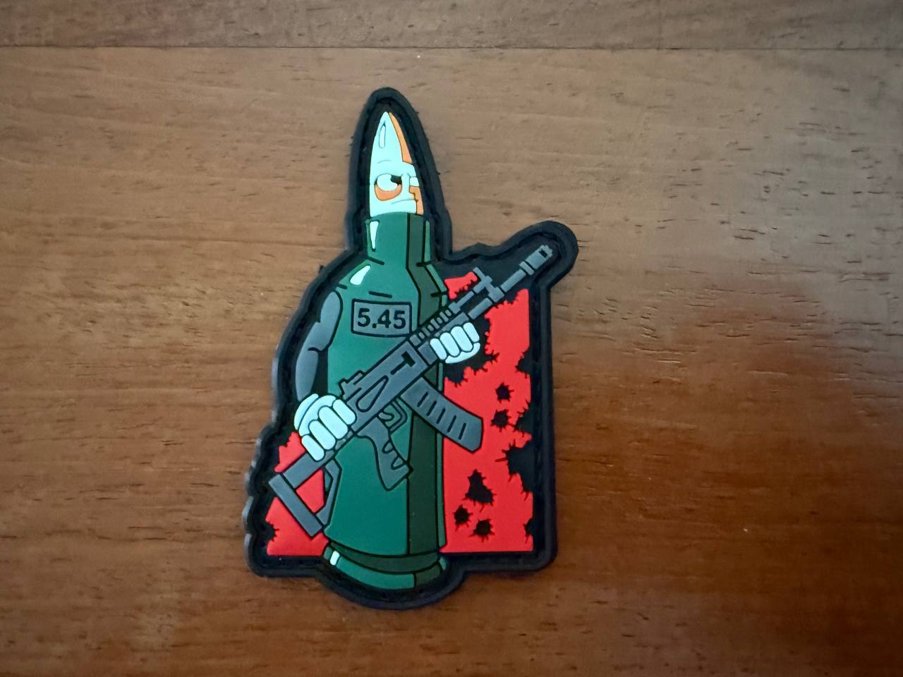 Patch of a green character holding a rifle on a wooden surface