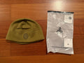 Russian TRIADA-TKO - Demi-season Fleece Hat - Olive - Size 60 displayed next to its clear branded packaging on a wooden surface, showcasing its compact and warm design.