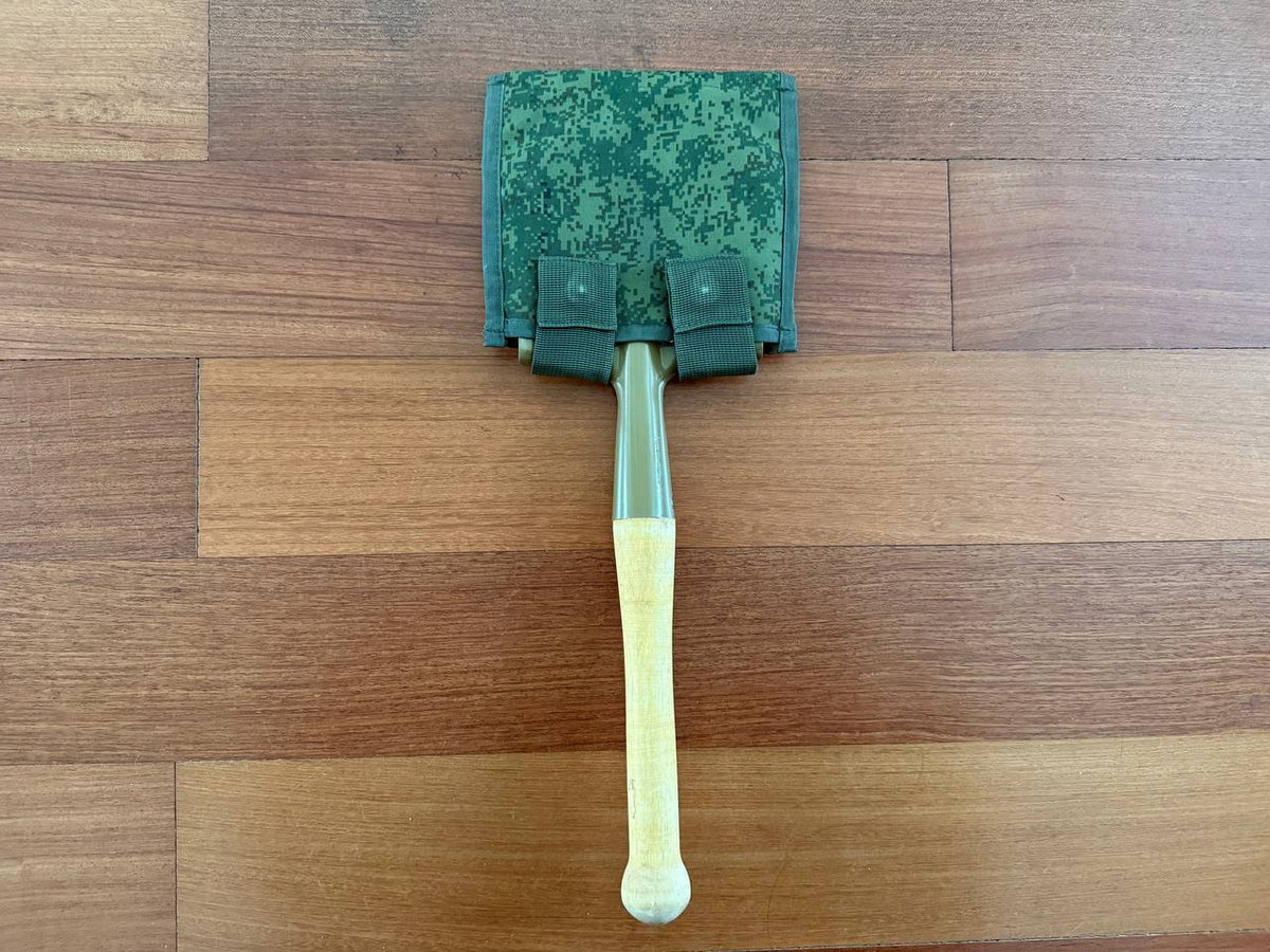 Russian Military Shovel & Tekhinkom Shovel Pouch Set with a wooden handle shovel featuring a green camouflage pouch, displayed on a hardwood floor, highlighting Russian surplus gear.