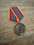 Close-up of a Russian FSB Medal "For Distinction in Military Service" - Replica, featuring a red and blue striped ribbon and detailed emblem on a wooden surface.
