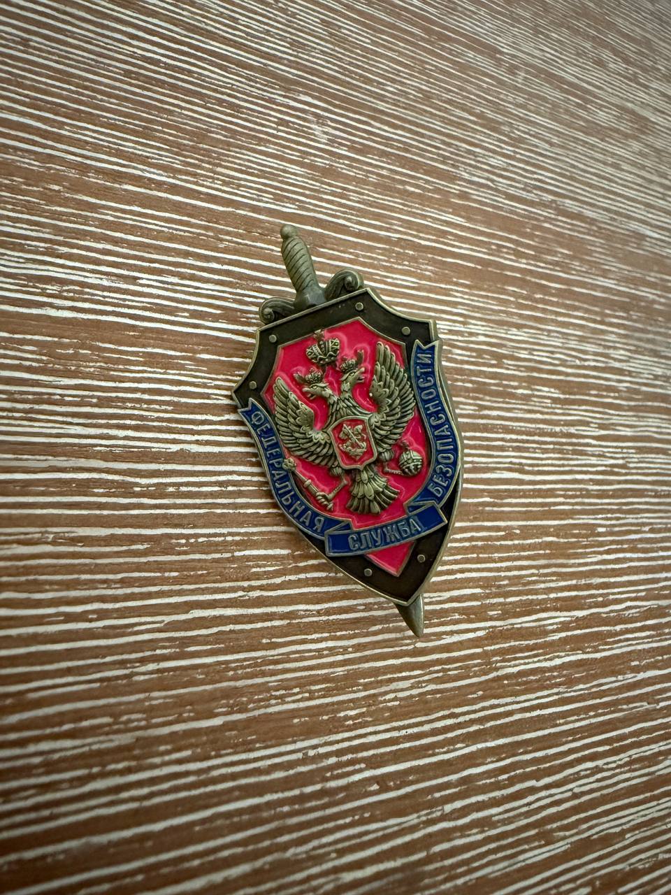 Russian FSB Pin – Shield & Sword featuring a detailed double-headed eagle emblem on a red and black shield background with Cyrillic text, representing Russian surplus craftsmanship.