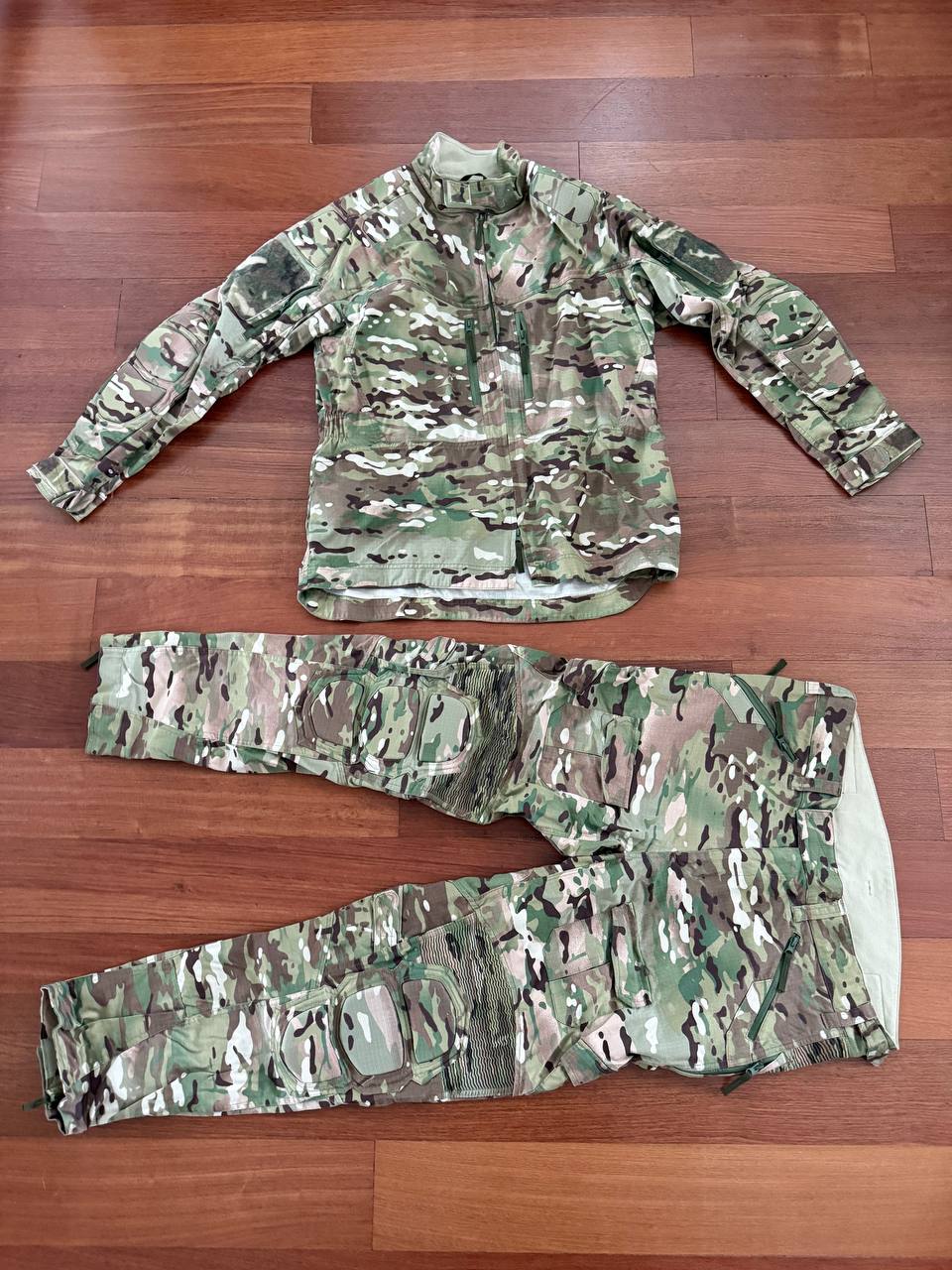 Russian Slavyanka FSB Contract Set – Multicam - Size 54/5 laid out on a wooden floor, featuring a camouflaged jacket and matching tactical pants designed for military use.