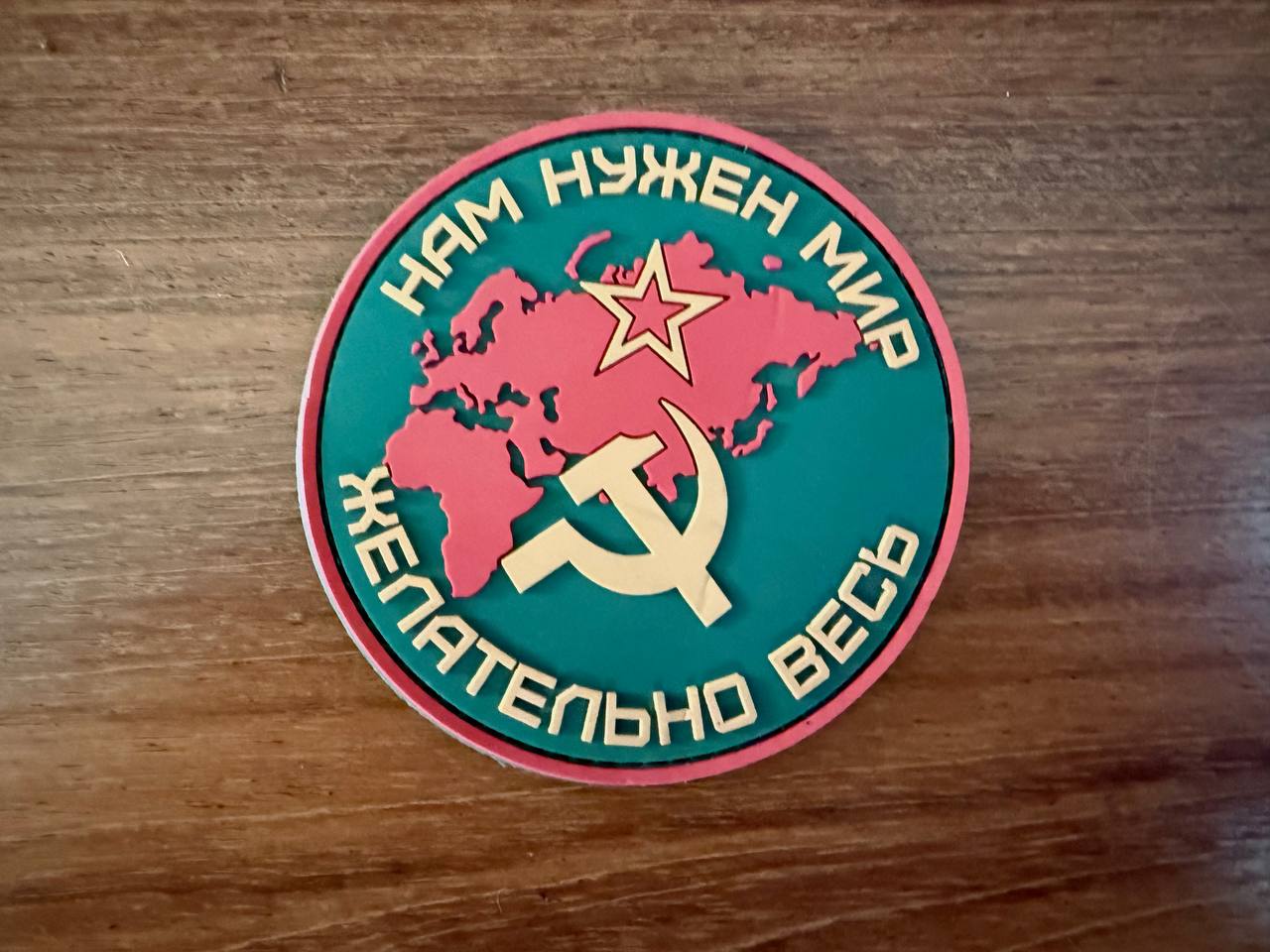 Russian "We need peace, preferably all of it" - Military Patch featuring a red map of the world with a Soviet star and hammer and sickle symbol on a green background.