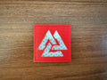 Russian Valknut Slavic/Norse Symbol 2x2' - Military Patch with a reflective silver Valknut design on a red fabric background, displayed on a wooden surface.