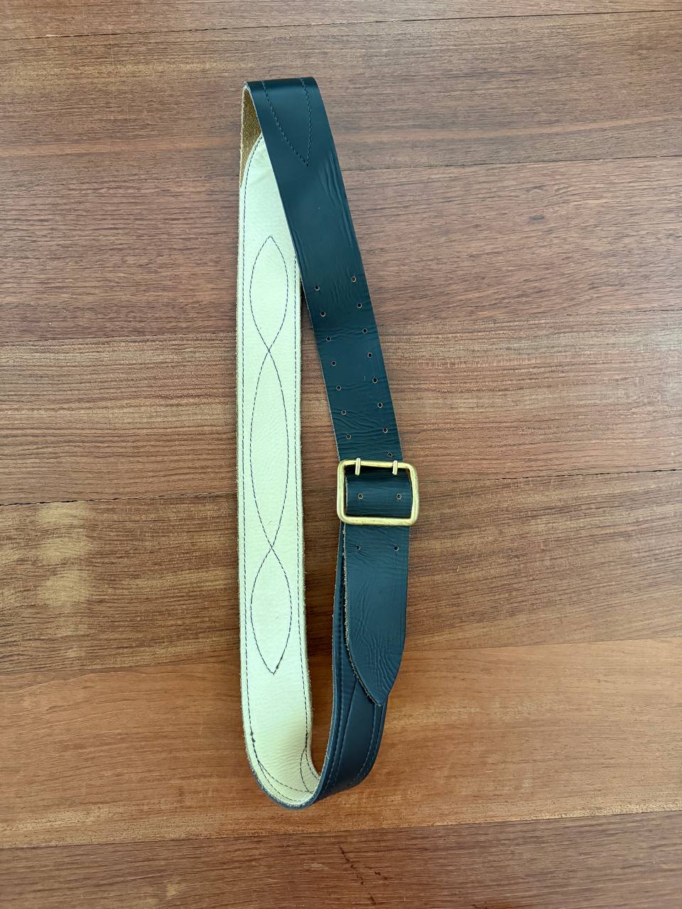 Russian Military Officer's Belt – Natural Leather with Brass Buckle lying flat on a wooden surface, showing black leather exterior and light-colored stitched interior.
