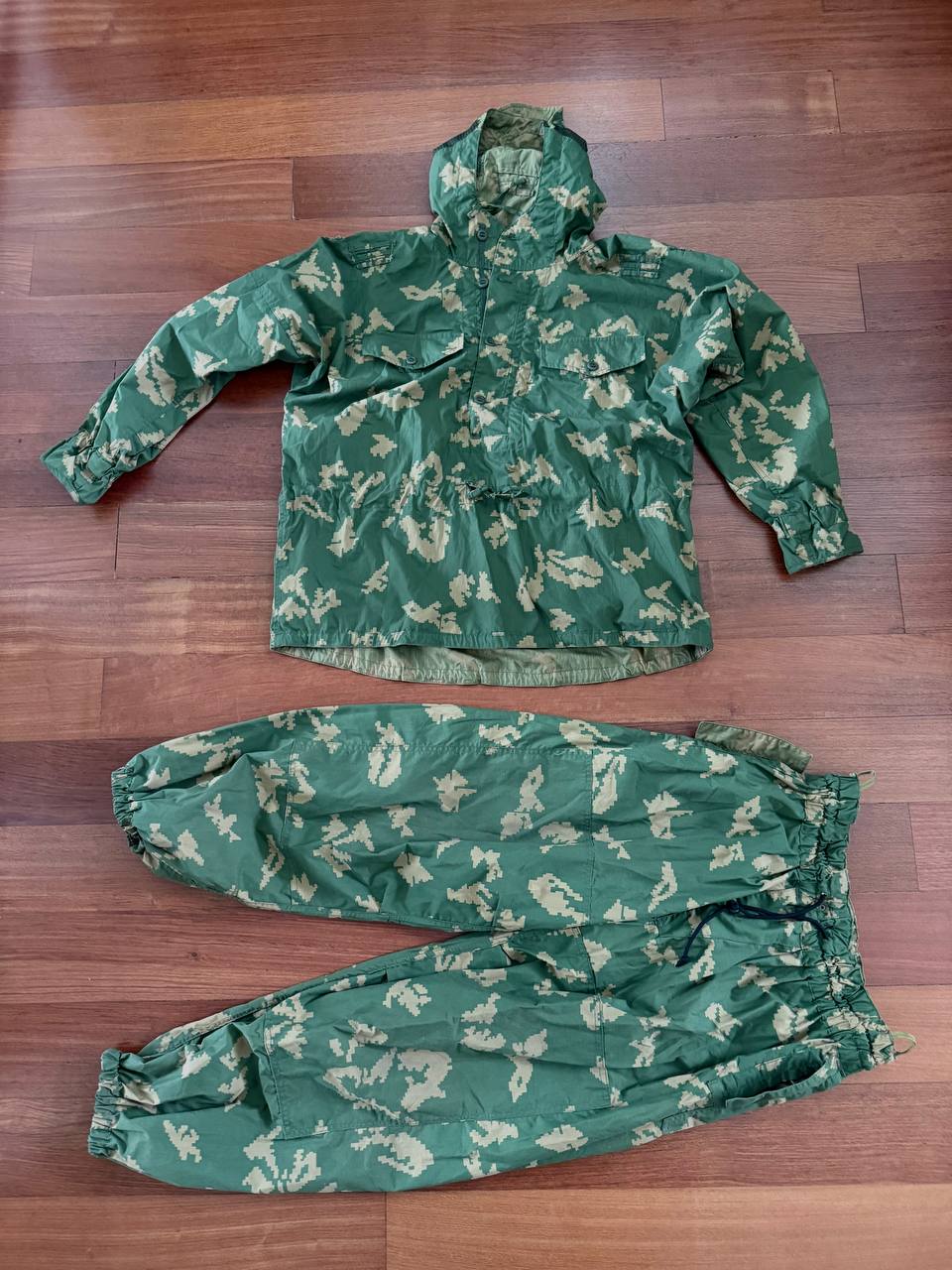 Russian SSO "Sumrak" Suit – Gold Dubok Color - Size 54-5 displayed on a wooden floor, featuring a camouflaged jacket with hood and matching pants, showcasing Russian surplus military apparel.