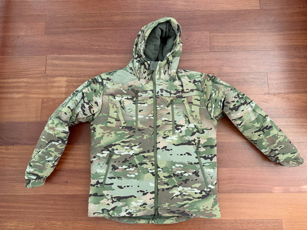 Russian Innovation Cold Weather Jacket (Layer 7) – Multicam - Size 54/5 laid flat on a wooden floor, featuring camouflage pattern and a hood designed for cold weather conditions.