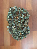 Russian FSB Practika Leaf Backpack Cover - 60L - Autumn Camo with 3D leaf-like fabric pieces creating a natural autumn camouflage pattern on a wooden floor background.