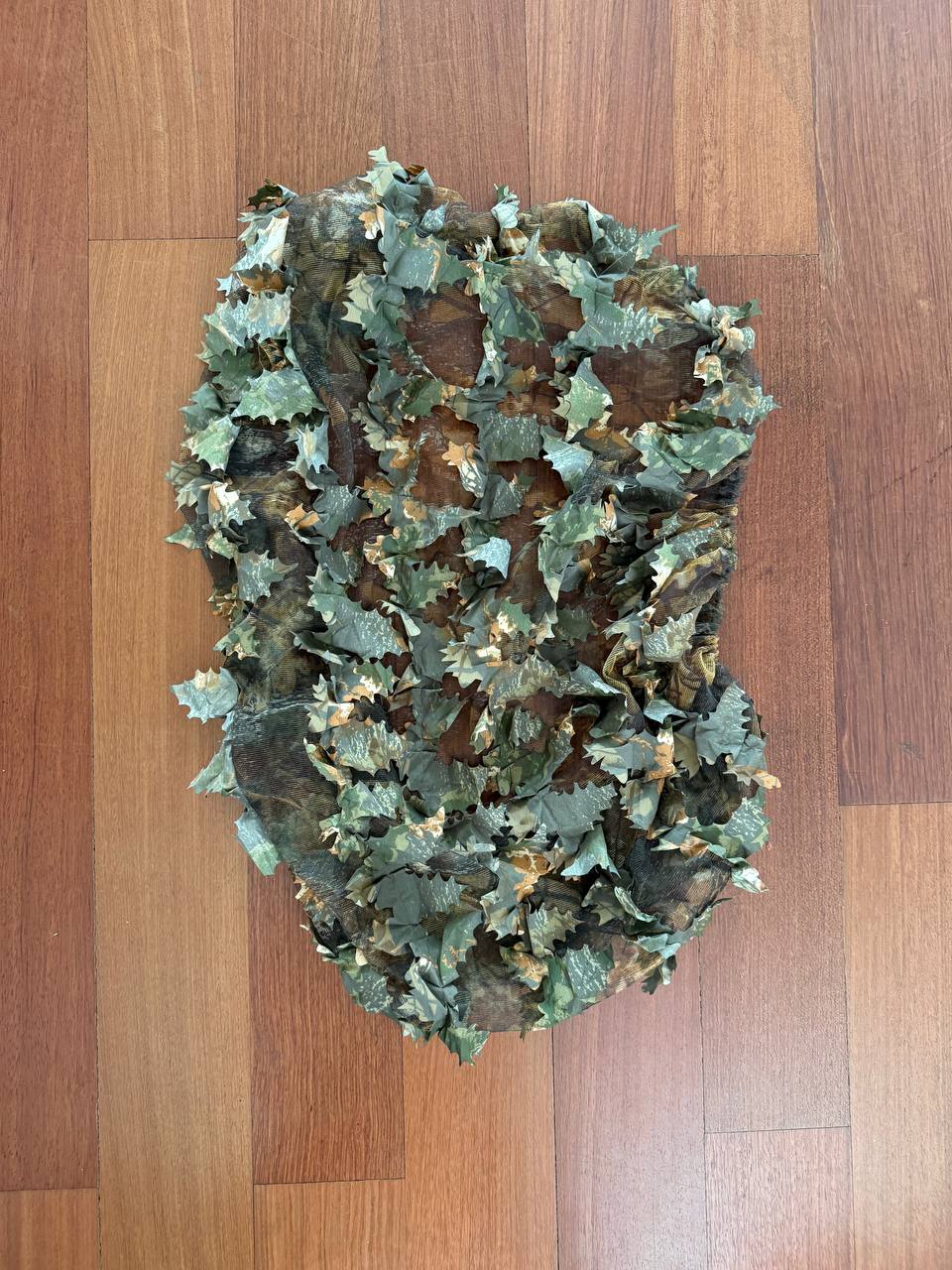 Russian FSB Practika Leaf Backpack Cover - 60L - Autumn Camo with 3D leaf-like fabric pieces creating a natural autumn camouflage pattern on a wooden floor background.
