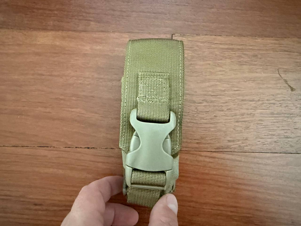 Tactical Single Grenade Pouch - Multicam in olive drab color, held by a hand, featuring durable nylon fabric and a sturdy plastic buckle closure.