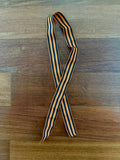 Russian St George Ribbon (100 Cm) - Military Commemorative Symbol featuring alternating black and orange stripes laid flat on a wooden surface.