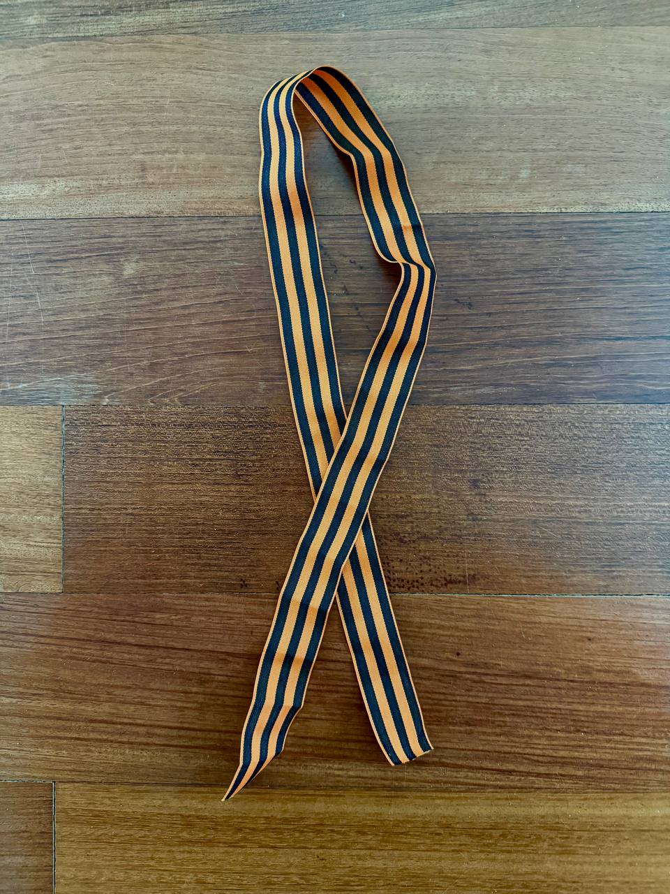 Russian St George Ribbon (100 Cm) - Military Commemorative Symbol featuring alternating black and orange stripes laid flat on a wooden surface.