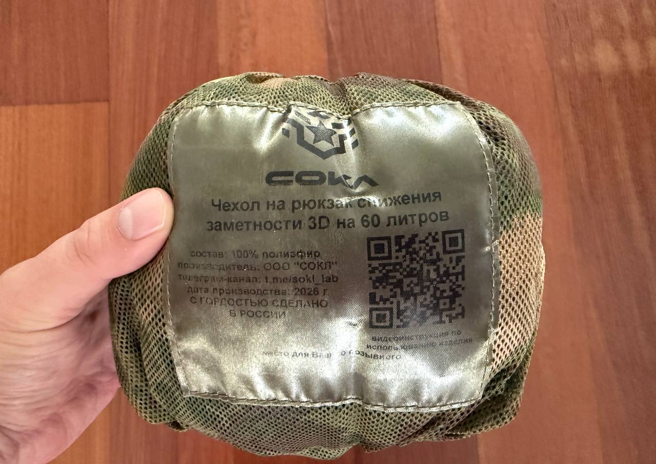 Russian Sokl Leaf Backpack Cover (60L) - Olja Pattern folded inside a compact olive green protective mesh bag with Russian text and a QR code visible on the label.