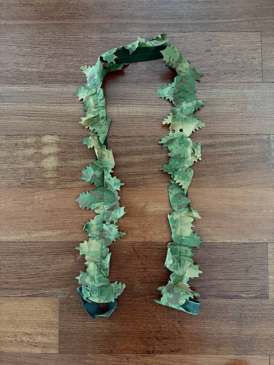 Russian Leaf Gun Stripe - 140cm - Olja Pattern laid out flat on wooden surface, featuring camouflaged fabric leaves in green shades for use as a Russian surplus accessory.