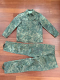 (USED) Russian 4 Layer Summer Suit - EMR Digital Flora - Size 54/5 displayed flat on a wooden floor, showing a green digital camouflage jacket and matching pants designed for Russian surplus enthusiasts.