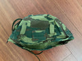 Russian 6b47 Helmet Cover - VSR98 - Size 2 in green and brown camouflage pattern lying flat on a wooden surface, showcasing fabric texture and attachment straps.