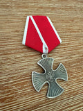Russian Order of Courage for Military Merit - Replica featuring a silver cross medal with a red and white ribbon, displayed on a wooden surface.
