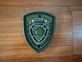 Belarus Spetsnaz "Tornado" Special Forces - Military Patch featuring an embroidered shield emblem with Cyrillic text on an olive green background, displayed on a wooden surface.