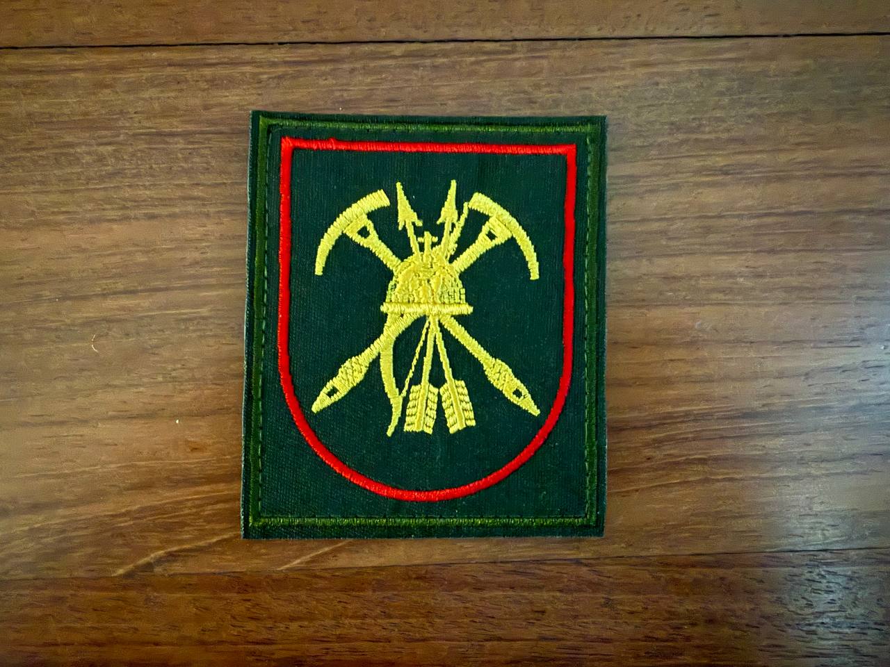 Russian 55th Separate Mountain Motorized Rifle Brigade - Military Patch featuring crossed yellow weapons and helmet on a dark green background with red border, Russian surplus style.