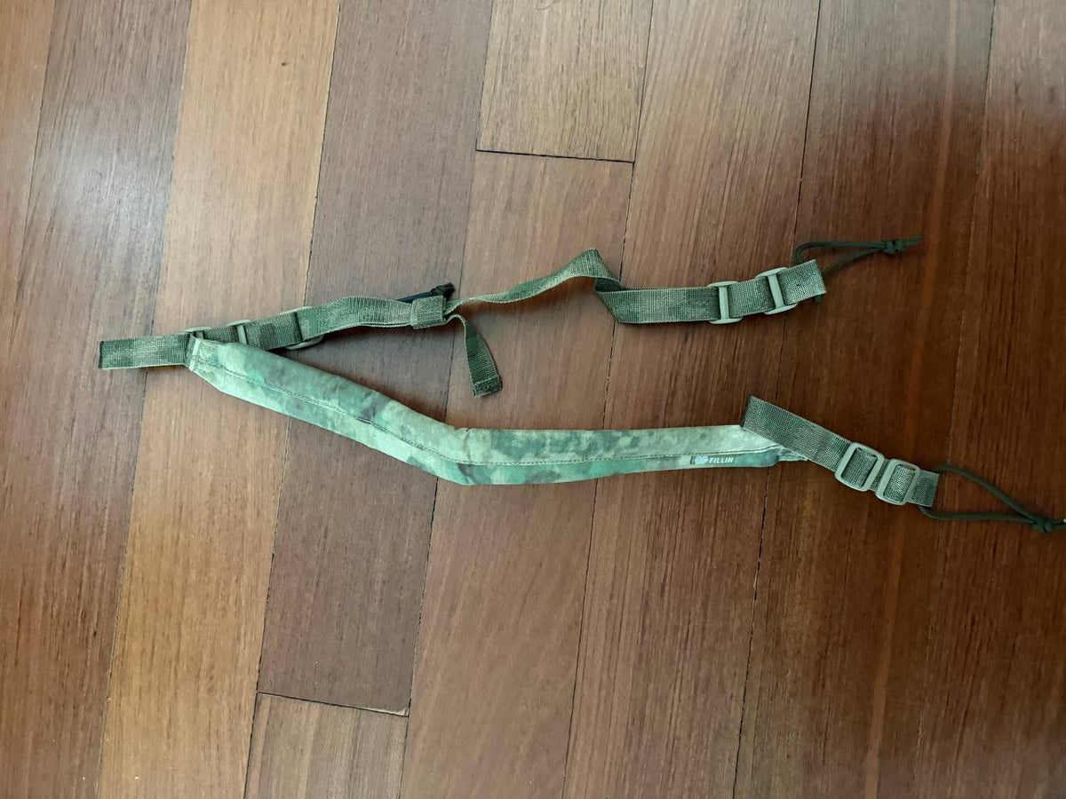 Russian Fillin Tactical Two-Point Gun Sling - A-TACS FG Moss displayed on a wooden floor, featuring adjustable straps and durable fabric with moss green camouflage pattern.