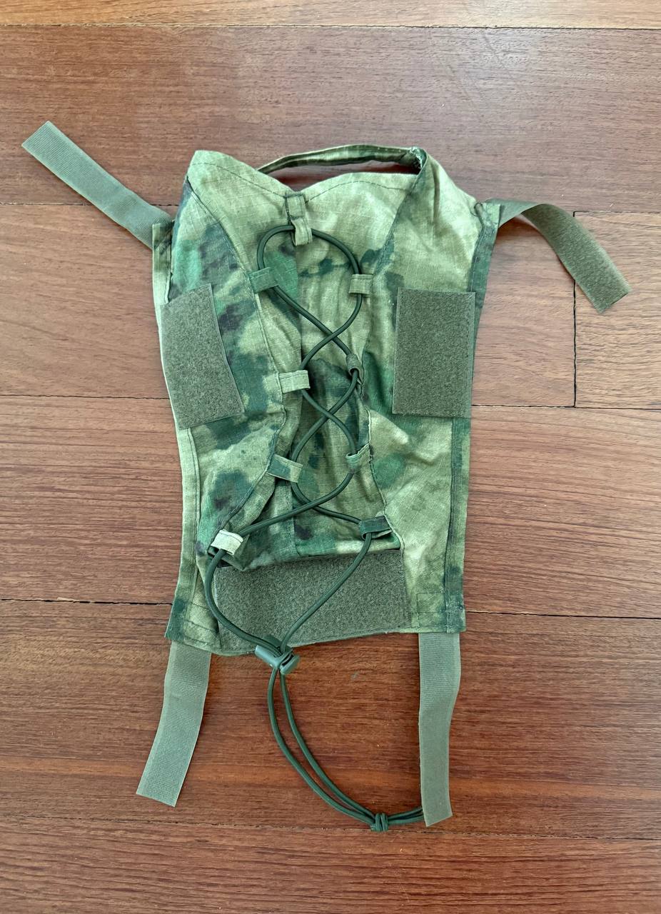 (USED) Russian Tactical Ops-Core FAST Helmet Cover - A-TACS FG/Moss Camo displayed flat on a wooden surface showing adjustable straps and cord lacing for secure fit, featuring camouflage pattern.