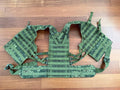 Russian Triada-TKO 6Sh117 Tactical Vest - EMR Camo laid flat on a wooden surface, displaying its adjustable straps and MOLLE webbing in distinctive Russian surplus green digital camouflage.