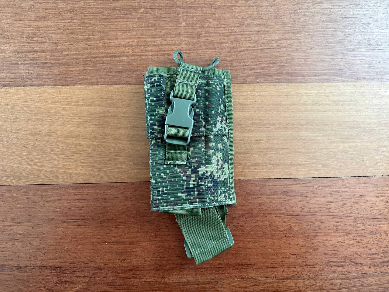 Russian Triada-TKO Tactical Radio Pouch - EMR Camo displayed on a wooden surface, showing digital camouflage pattern and secure buckle closure.