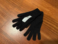 Pair of black knitted gloves laid flat on a wooden surface featuring a white label with size details, identified as Russian Army BTK Group Ratnik Wool Gloves - Black - Size 22.