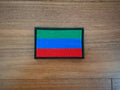 Embroidered Russian Republic of Dagestan Flag - Military Patch with green, blue, and red horizontal stripes on a wooden surface.