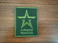 Green embroidered patch featuring a stylized star and Cyrillic text, representing the Russian Armed Forces Insignia - Military Patch, displayed on a wooden surface.