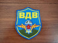 Russian Airborne Forces VDV - Military Patch with blue shield, yellow Cyrillic lettering, parachute and wings emblem, and red star on wooden background, representing Russian surplus.