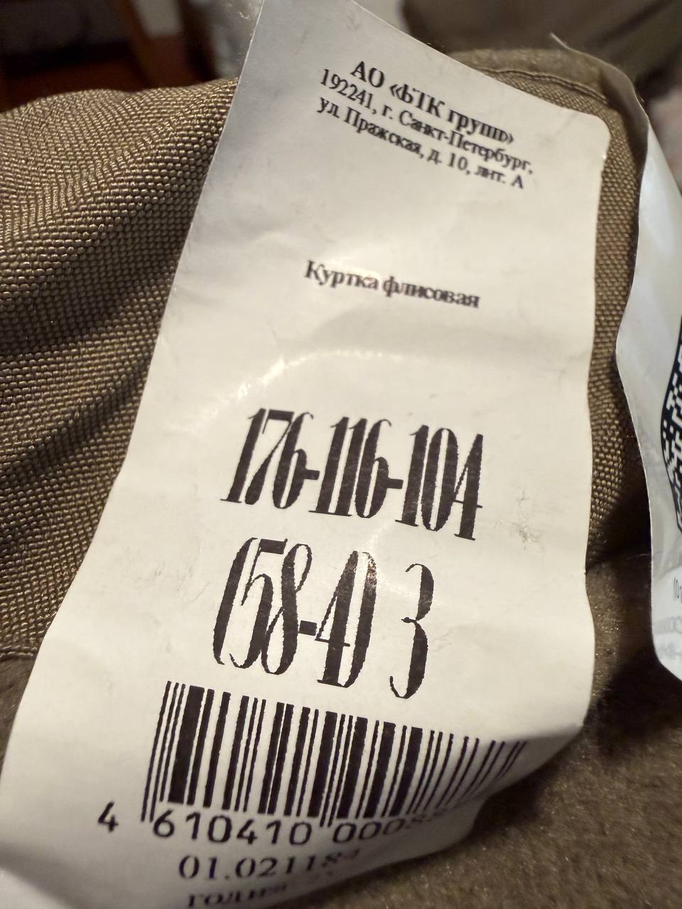 Close-up of a clothing label inside a Russian BTK Group - VKPO 2.0 Fleece Jacket – Size 58/4 showing size and manufacturing details on light brown fabric.