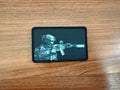 Black patch with a soldier and rifle design on a wooden surface