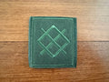 Green embroidered patch on a wooden surface